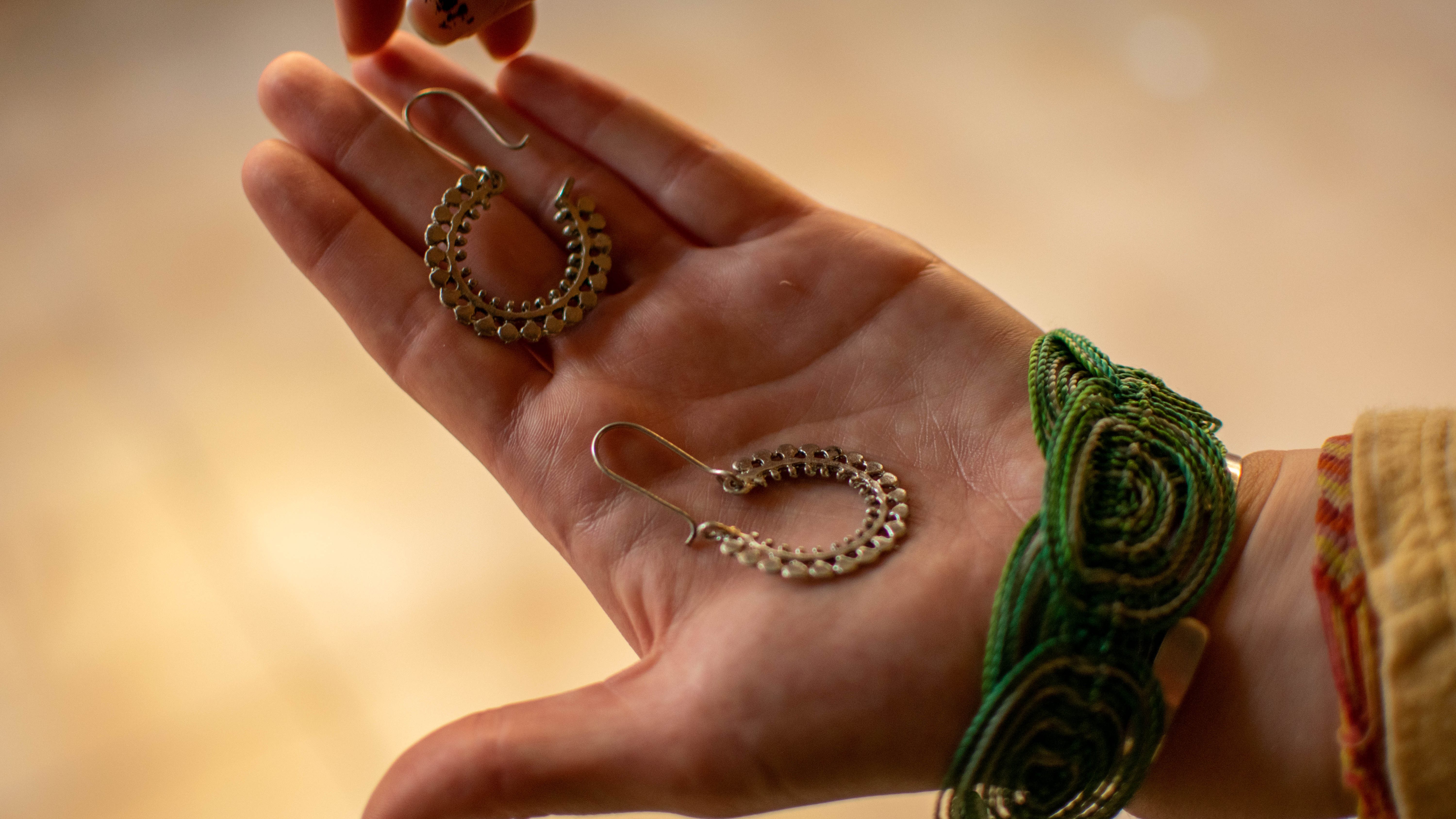 hand holding two silver earrings